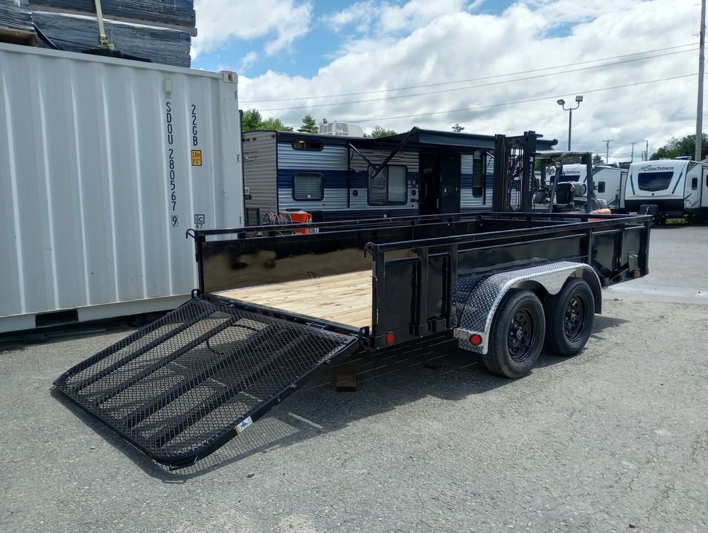 2024 PJ Trailers 14 ft Utility – Solid Metal Sides – Three-quarter rear view with the mesh ramp gate lowered to the ground