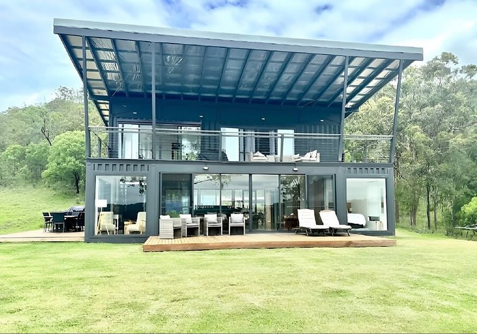 3-Bedroom Two-Story Container Home – Upper Terrace & Patio – Full-height glazing across the ground floor opens the living, kitchen and dining zone to the outdoors