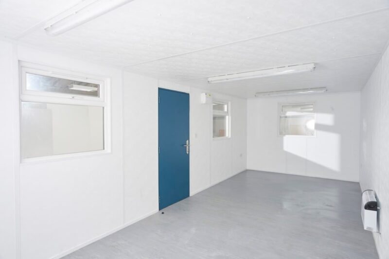 24 x 10 ft Jackleg Cabin – Goosewing Gray – Interior view of the empty cabin with white walls, windows, and ceiling lights