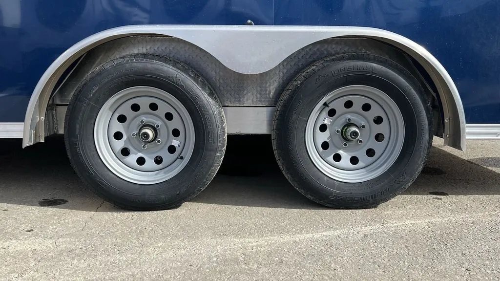 2023 High Country 14 ft Trailer – Blue, Drive-Through – Close-up of the dual axles with silver modular wheels and black tires