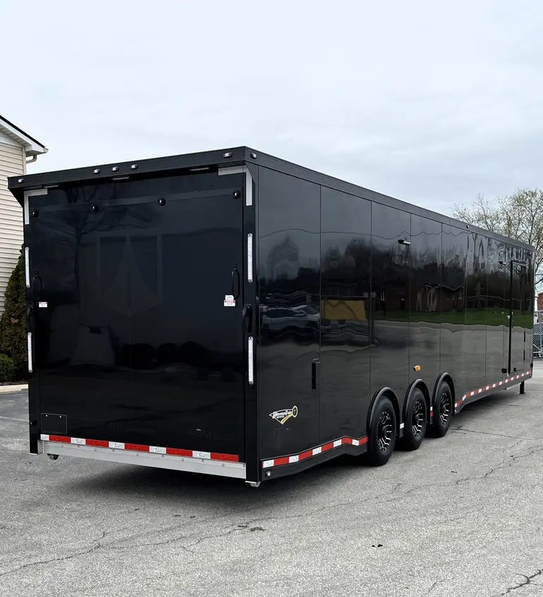 2025 ATC 44 ft Car Hauler – Premium Escape Door – Three-quarter rear view of a long black enclosed gooseneck trailer