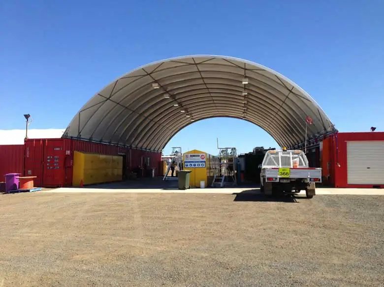 Container Shelter – Domed Tensile Membrane Cover – Full frontal view of a wide arched shelter mounted on red containers