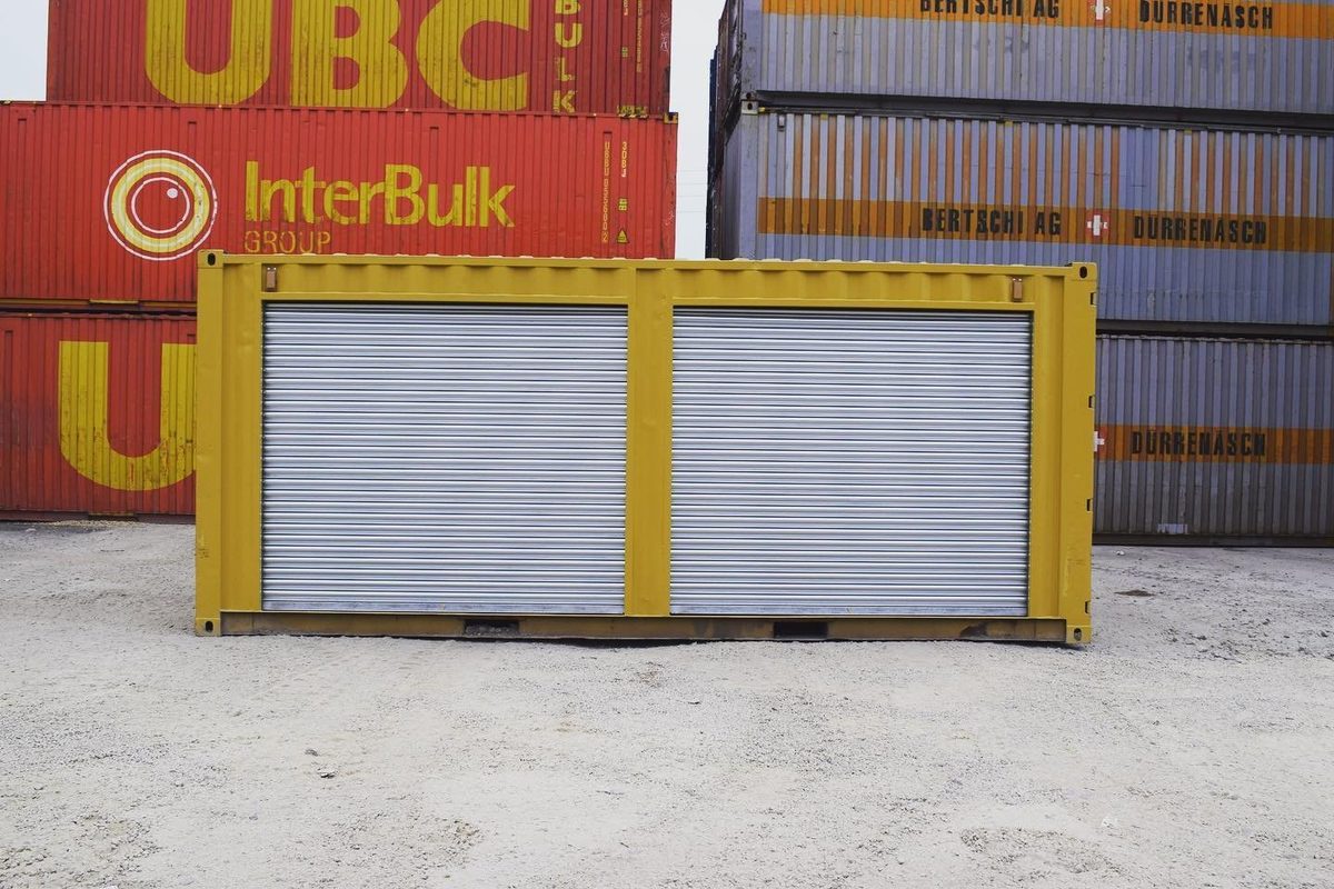 20ft Used Storage Container – Dual Side Roll-Up Doors – Yellow storage container with two closed silver roll-up doors in a container yard