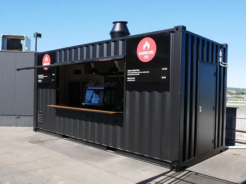 Shipping Container Kitchen – Insulated, Lockable – Matte black shipping container with open hatch and red barbecue pit signage