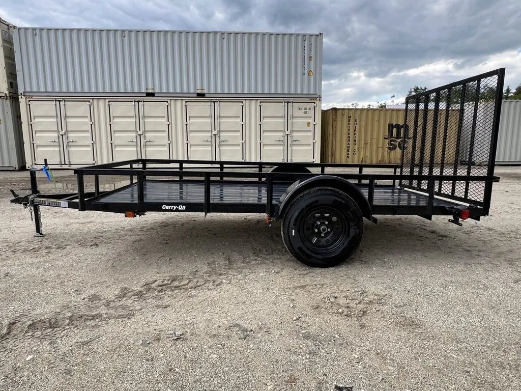 2024 Carry-On 12 ft Utility Trailer – Rear Ramp Gate – Left side profile view of the utility trailer against white shipping containers