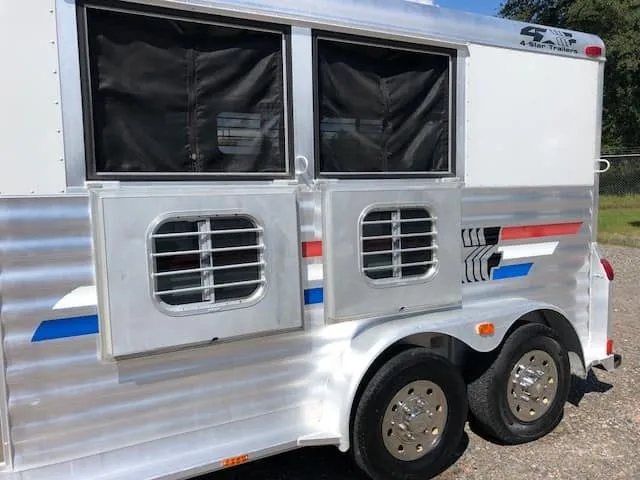 2004 4 Star 2 Horse Gooseneck Trailer – Slant Load, White – Close-up of the drop-down feed windows with bars and dual axles with chrome wheels