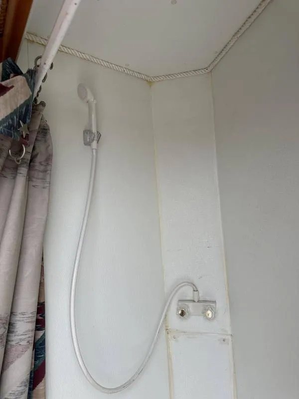 2004 Hart 3 Horse Gooseneck Trailer – Weekender Living Quarters – A wall mounted shower head and faucet handles inside the bathroom