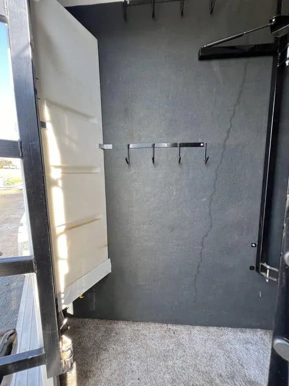 2020 Trails West Sierra 4 Horse Gooseneck – Comfort Package – Tack room interior with wall hooks and dark gray carpeted walls