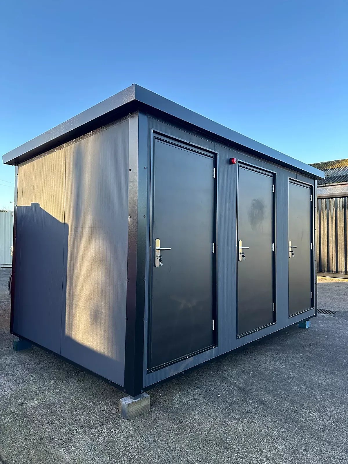 Custom Shipping Container Restroom – Three Private Compartments – three-quarter exterior view of restroom unit with three closed doors