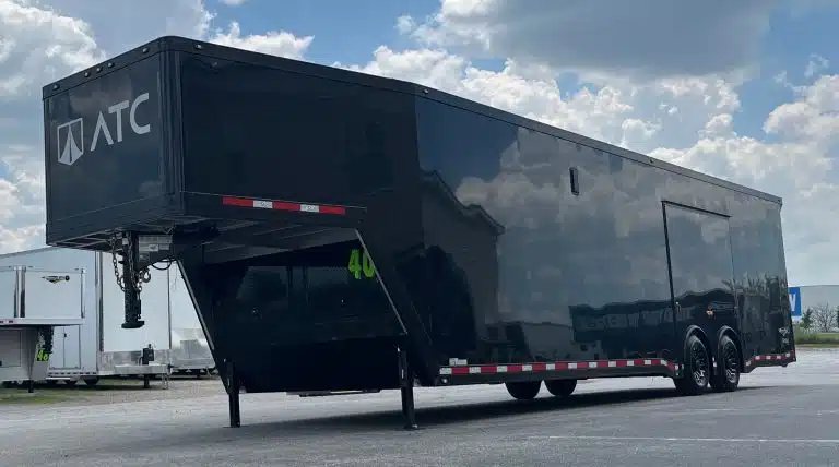 2026 ATC 40 ft Gooseneck – Black Trim – Front three-quarter view of the black gooseneck car trailer against a cloudy sky