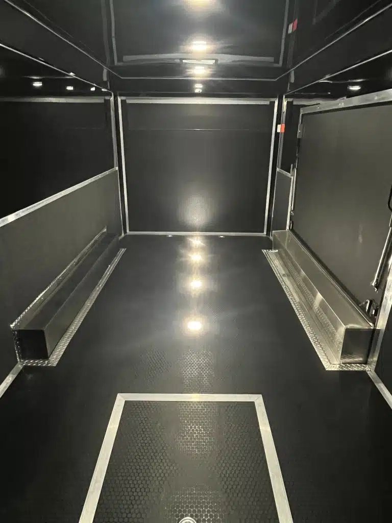 2026 Haulmark 20 ft Car Trailer – Large Escape Door – Interior view looking towards the rear with black walls and coin flooring