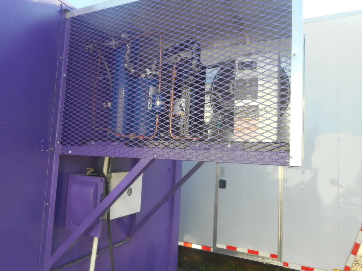 20ft Refurbished Cold Storage Container – Freezer/Cooler – refrigeration equipment behind purple protective mesh beside white trailer