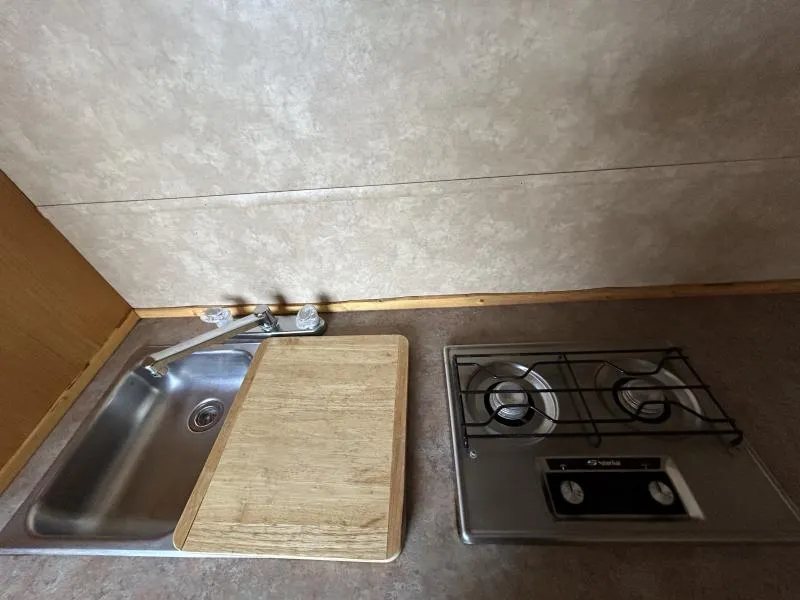 2002 Silverado 3 Horse Gooseneck Trailer – Wood Interior – Close-up of a stainless steel kitchen sink and a two-burner gas stove