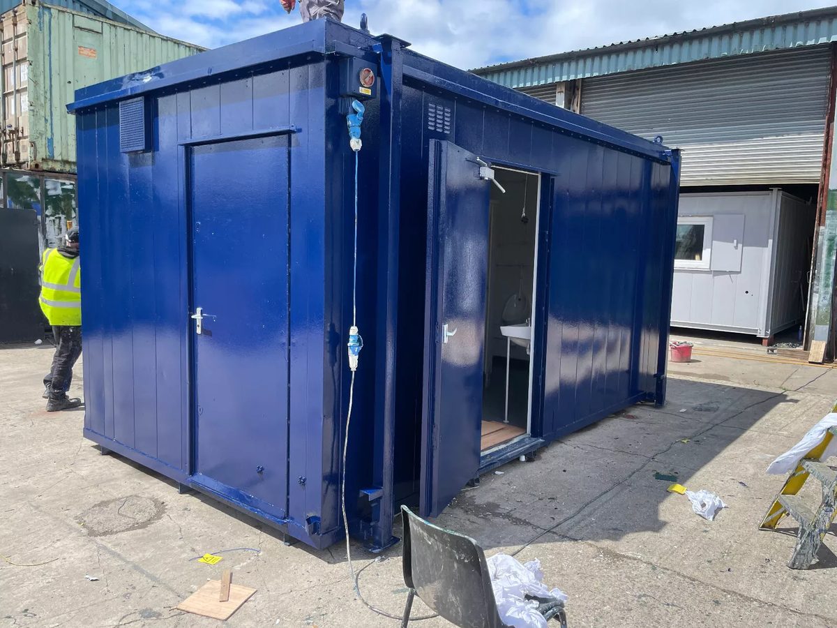 16ft × 9ft Modular Toilet Block – 3+1 Compartment Layout – Three-quarter exterior of blue toilet block with one door open