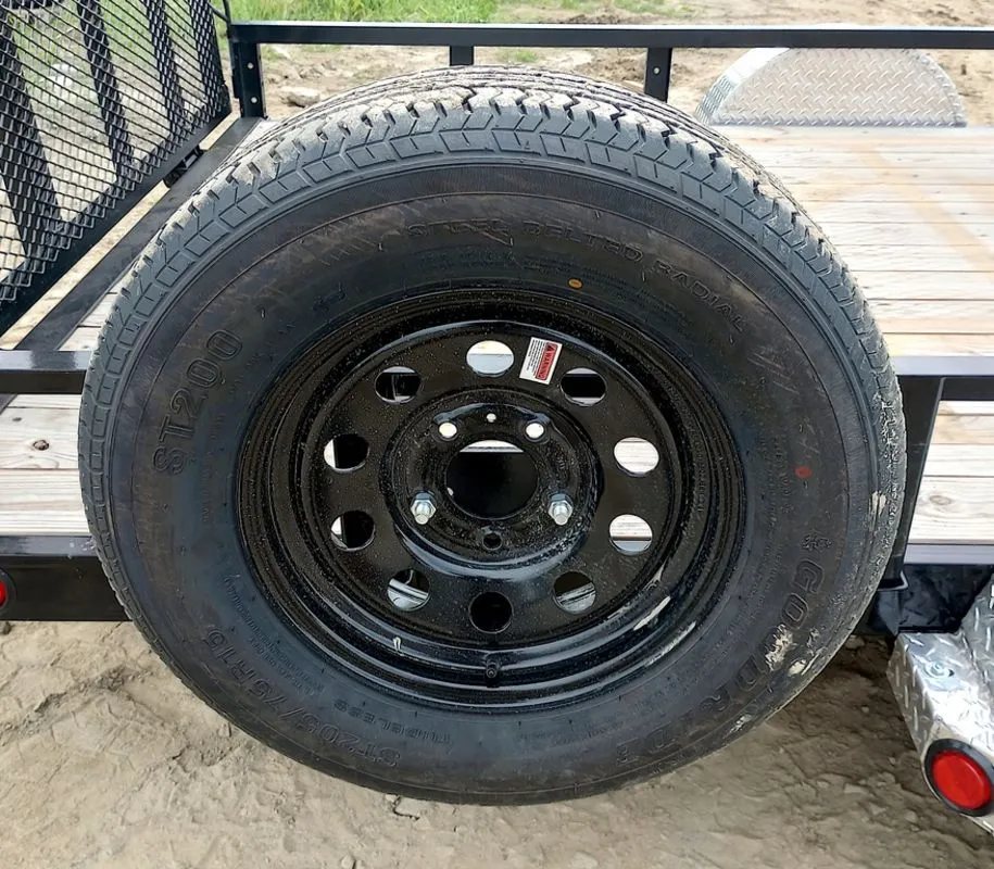 2024 PJ Trailers 14 ft Utility – Side Loading Ramps – Side mount spare tire attached to the rail of the black utility trailer