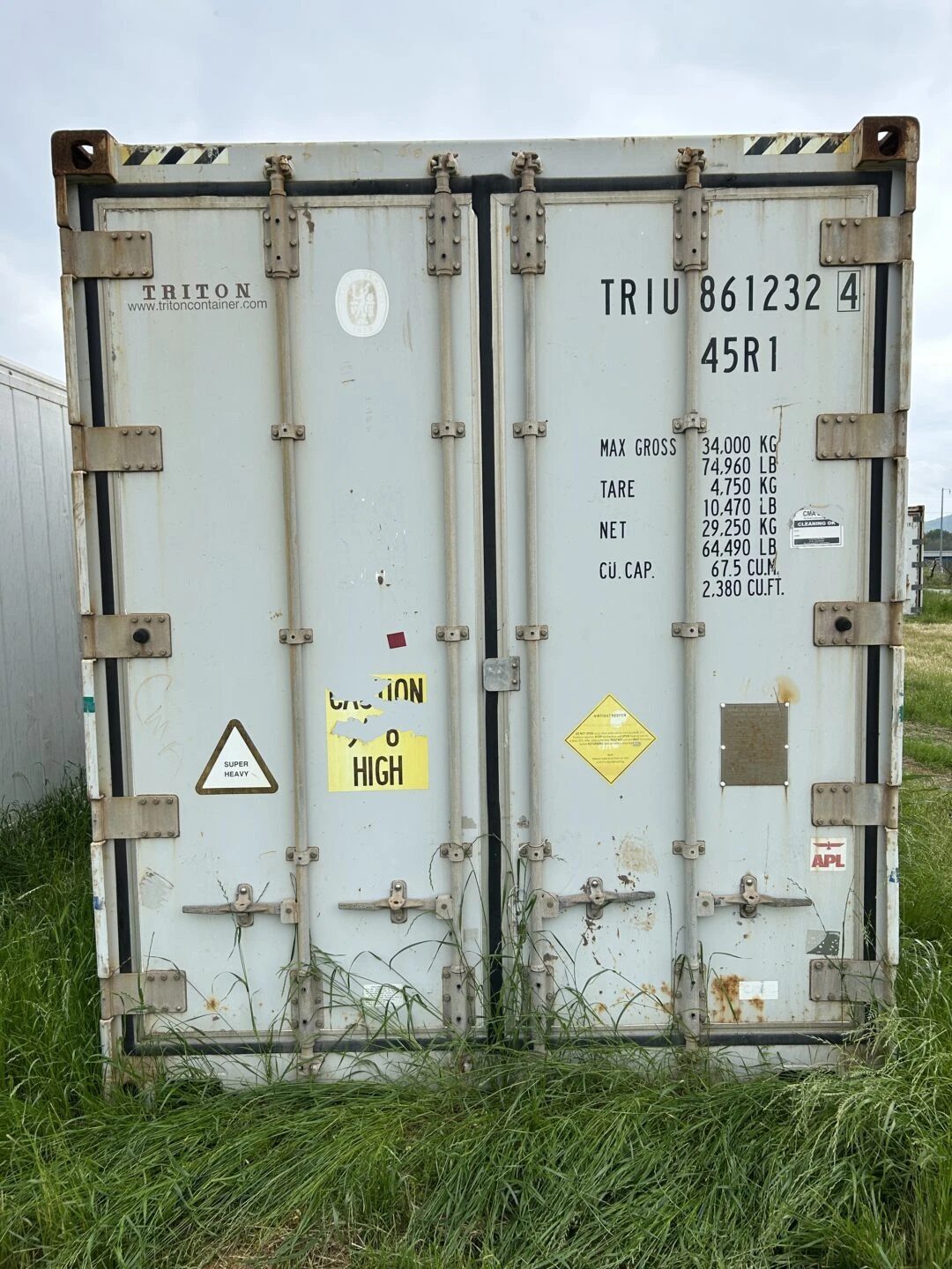 40ft High Cube Refrigerated Container – Insulated Storage – closed refrigerated container cargo doors surrounded by tall grass