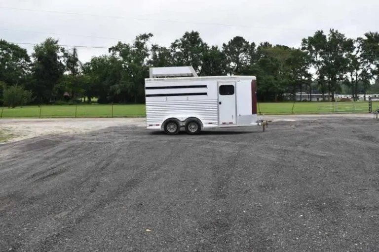 2012 CM 3 Horse Bumper Pull Trailer – Aluminum, Hayrack – Distant side view of the trailer parked on a gravel lot under overcast sky