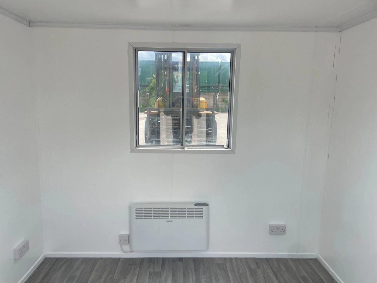 10ft Shipping Container – Unfitted Office Conversion Base – empty office interior with window, wall heater and grey flooring