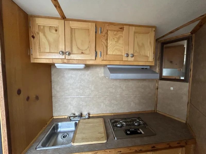 2002 Silverado 3 Horse Gooseneck Trailer – Wood Interior – Kitchenette area with wooden upper cabinets, range hood, and sink