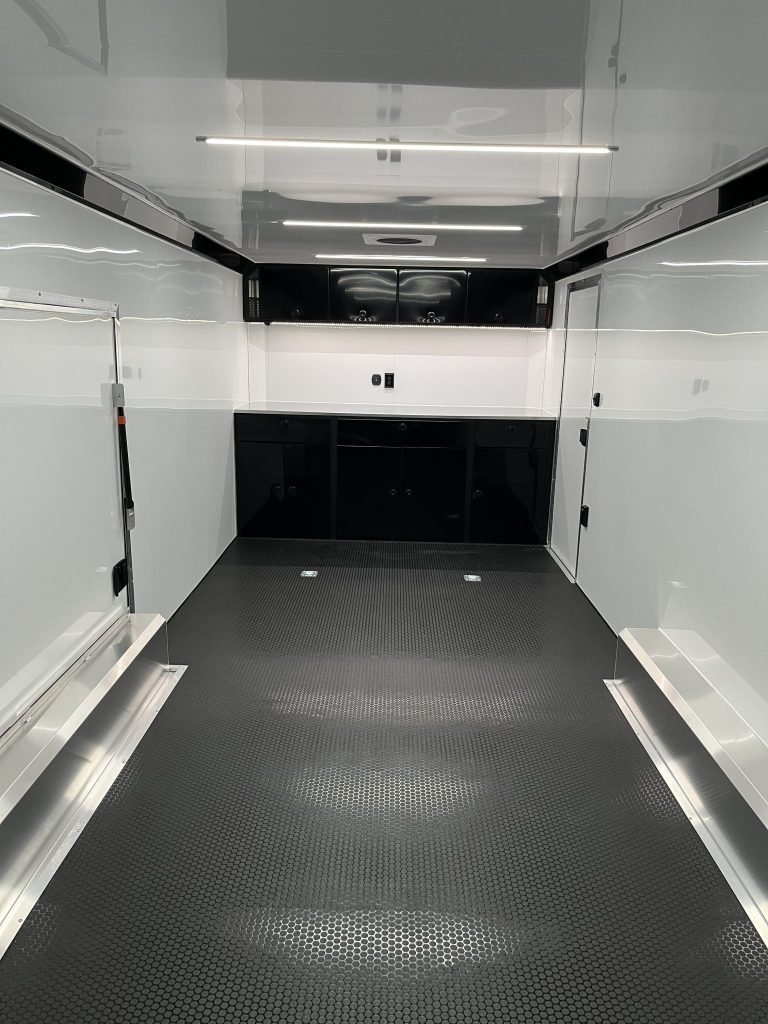 2026 ATC 24 ft Car Hauler – Black, Plus Package – Interior view facing forward showing black storage cabinets and clean white walls