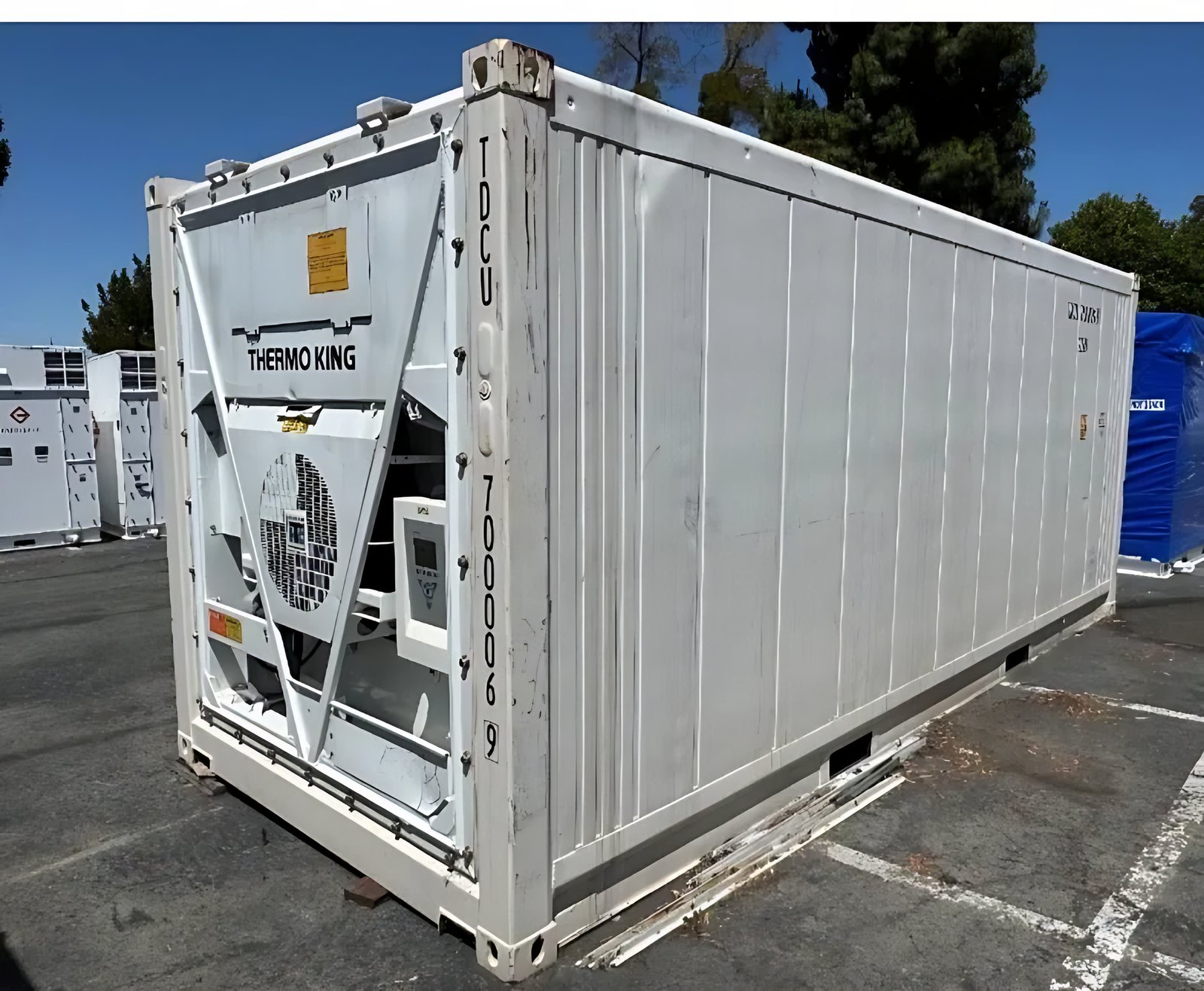 20ft Used Refrigerated Shipping Container – Thermo King – White refrigerated container showing front cooling equipment and long side in paved yard
