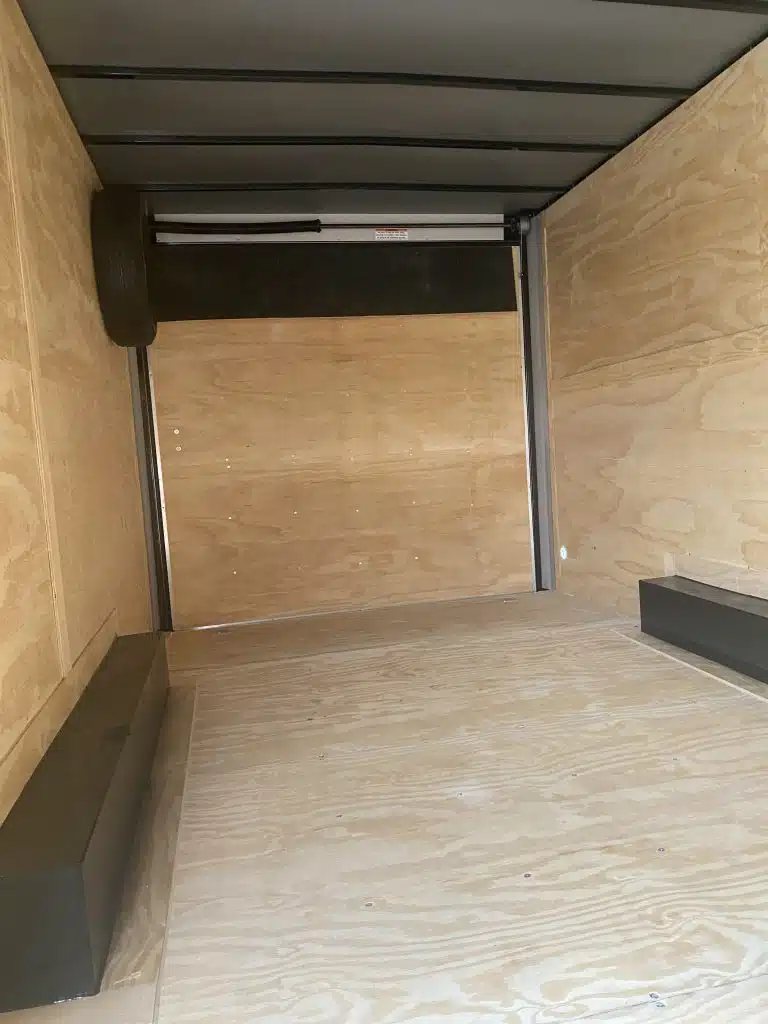 2026 Millennium 20 ft Car Trailer – Extra Height – Empty interior of trailer with plywood walls and floor showing wheel wells