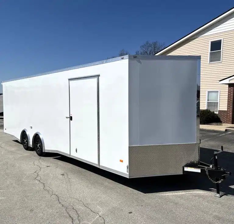 2025 Millennium Blaze 26 ft Car Hauler – Cabinets – A three-quarter exterior view of a white enclosed car hauler trailer with side door