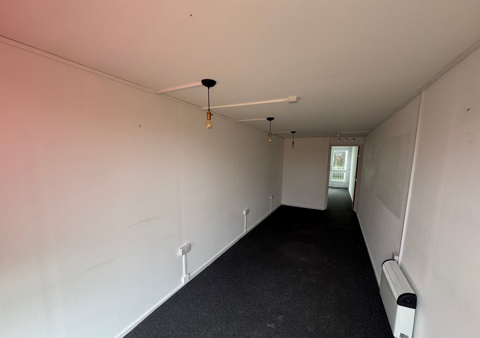 40ft Container Home – Two-Room Conversion – The interior of this two-room converted container features installed electrical outlets and finished white walls