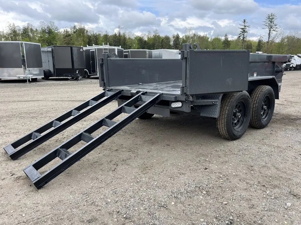 2024 RawMaxx 10 ft Dump Trailer – Shadow Grey – Rear view showing two loading ramps extended from the back of the trailer bed