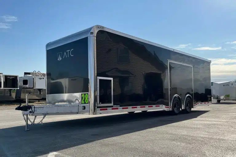 2026 ATC 28 ft Car Trailer – Premier Package – Front three-quarter view of a black enclosed trailer on asphalt