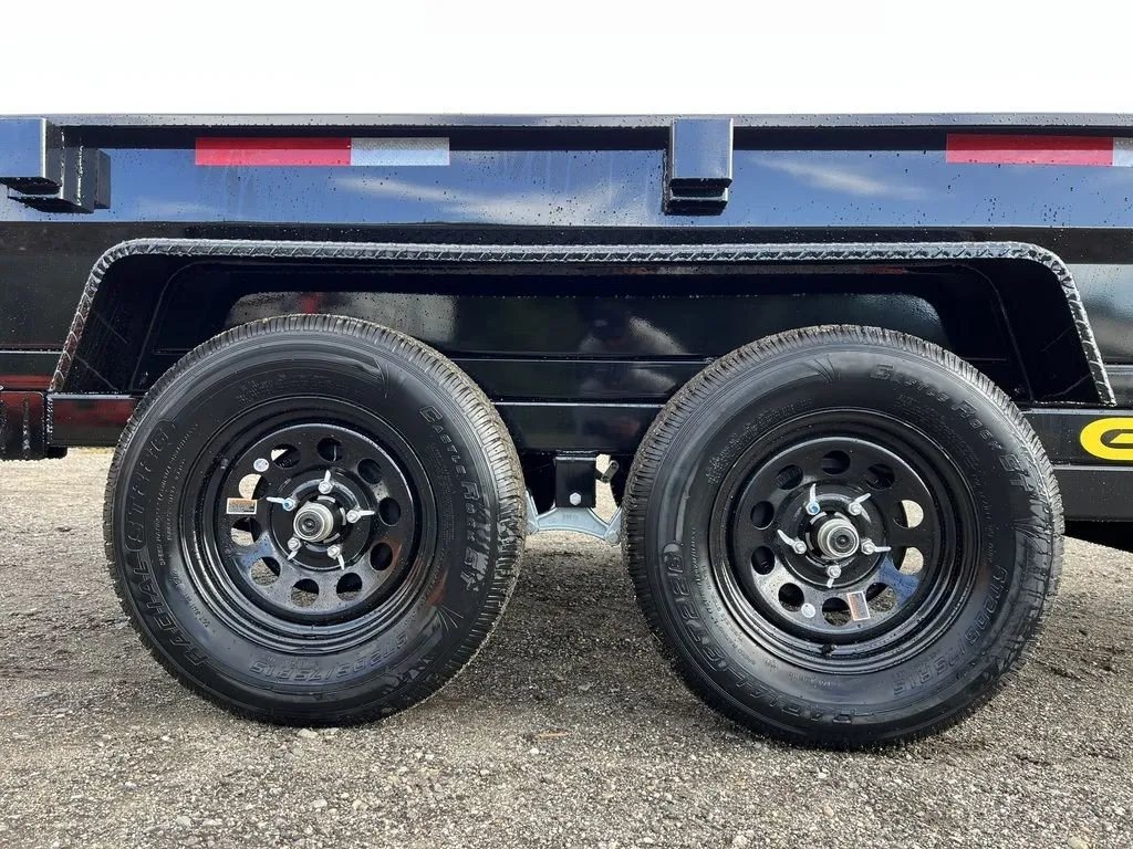 2024 Griffin Trailers 10 ft Dump – Barn Door Gate – Close-up of the dual axles and black wheels on the gravel surface