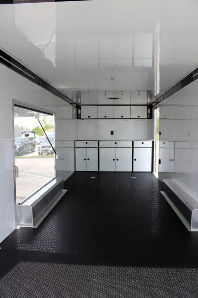 2026 ATC 24 ft Car Trailer – Silverfrost, Plus Package – Interior view facing forward showing white cabinets and black flooring