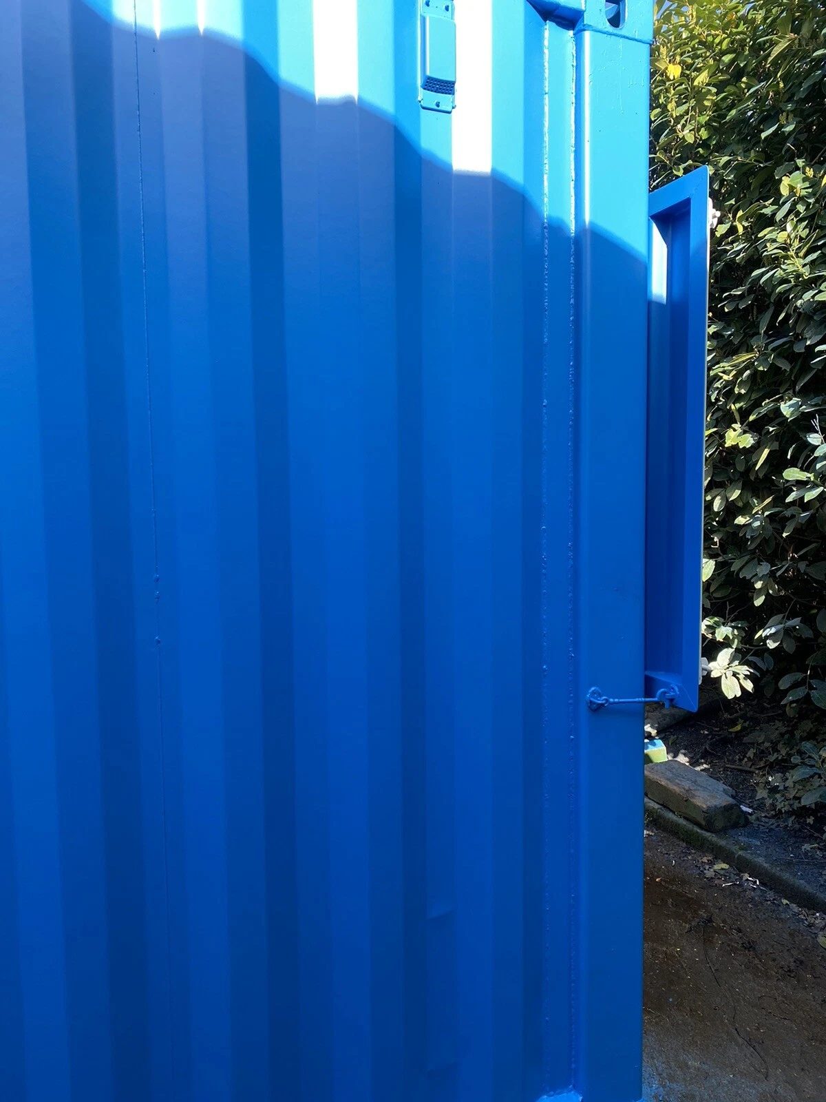15ft Custom Container Bar & Kiosk – Side Service Hatches – close-up of blue corrugated container wall and hinged panel