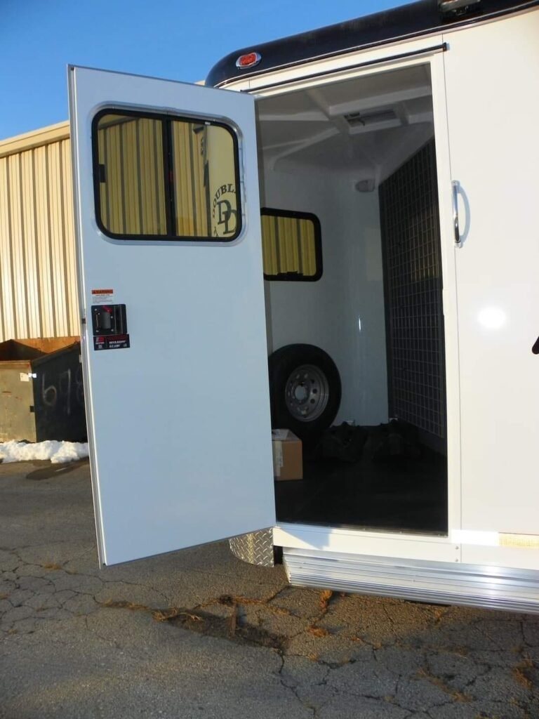 2022 Double D 2 Horse Bumper Pull – Reverse Slant – Side access door open showing interior storage area and spare tire