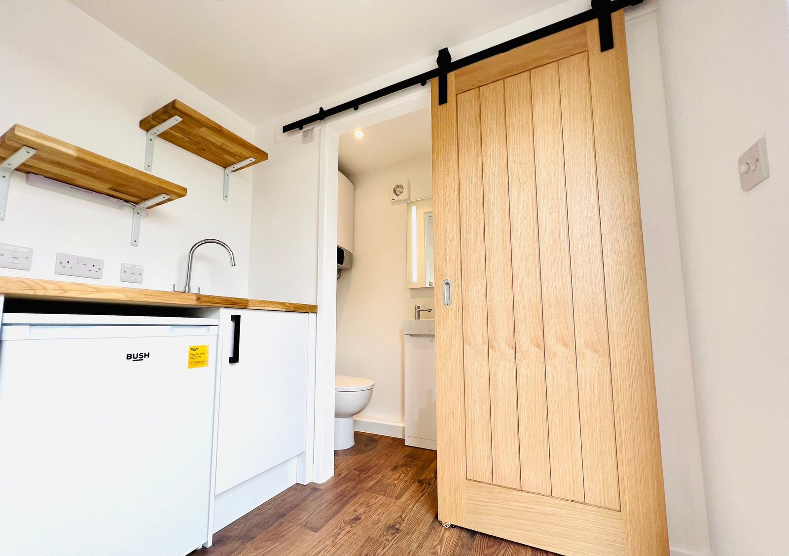 20ft Container Home – One Bed Box, 1 Bedroom – A light wood barn door separates the functional kitchenette from the private bathroom in this 20ft container conversion