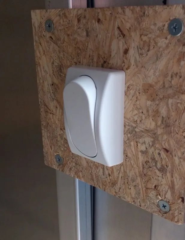 2024 Mission Trailers 12 ft Powersports – Side X Side – A white rocker light switch mounted on a small piece of wood inside