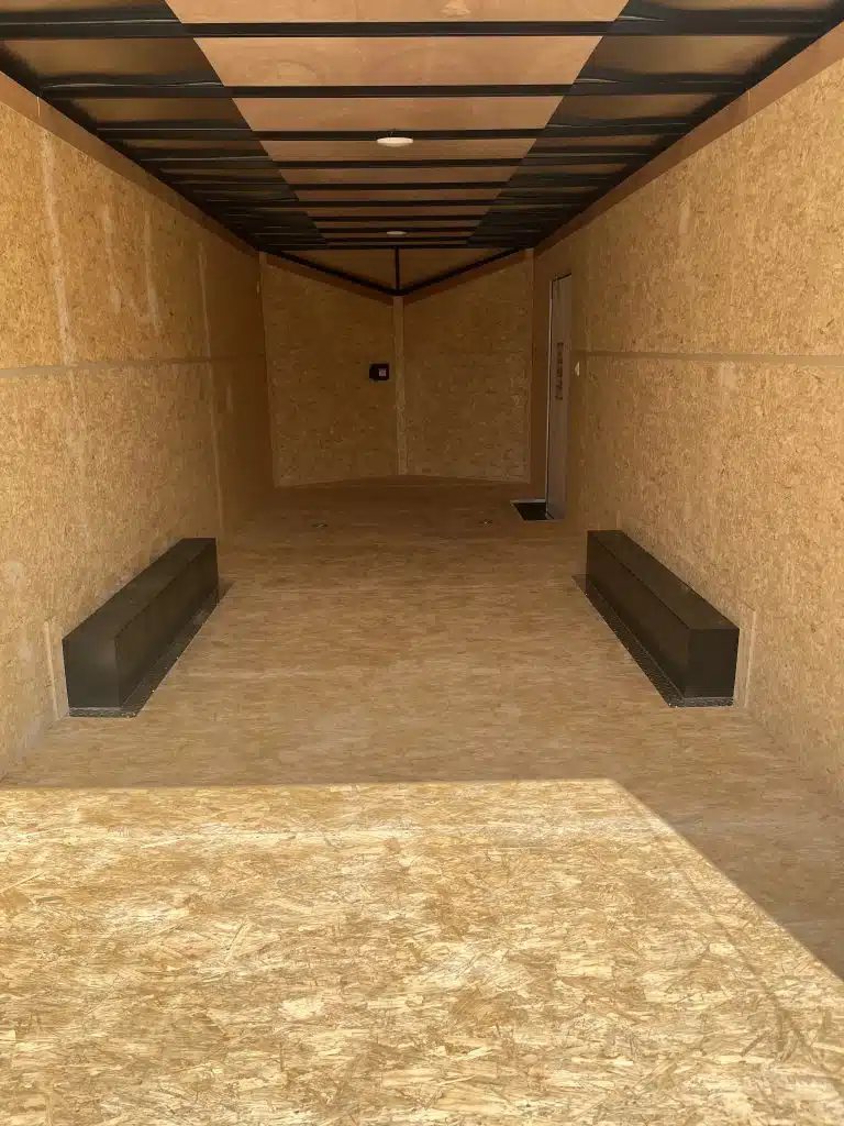 2026 Millennium Hero 24 ft Car Hauler – Gray Dove – Empty interior of the trailer featuring wood walls, wood floor, and black wheel wells