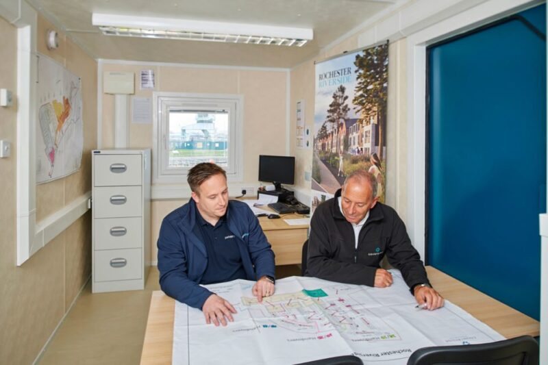 32 ft ECOlink Meeting Room Cabin – Blue – Two men sitting at a table inside a portable office reviewing architectural site plans