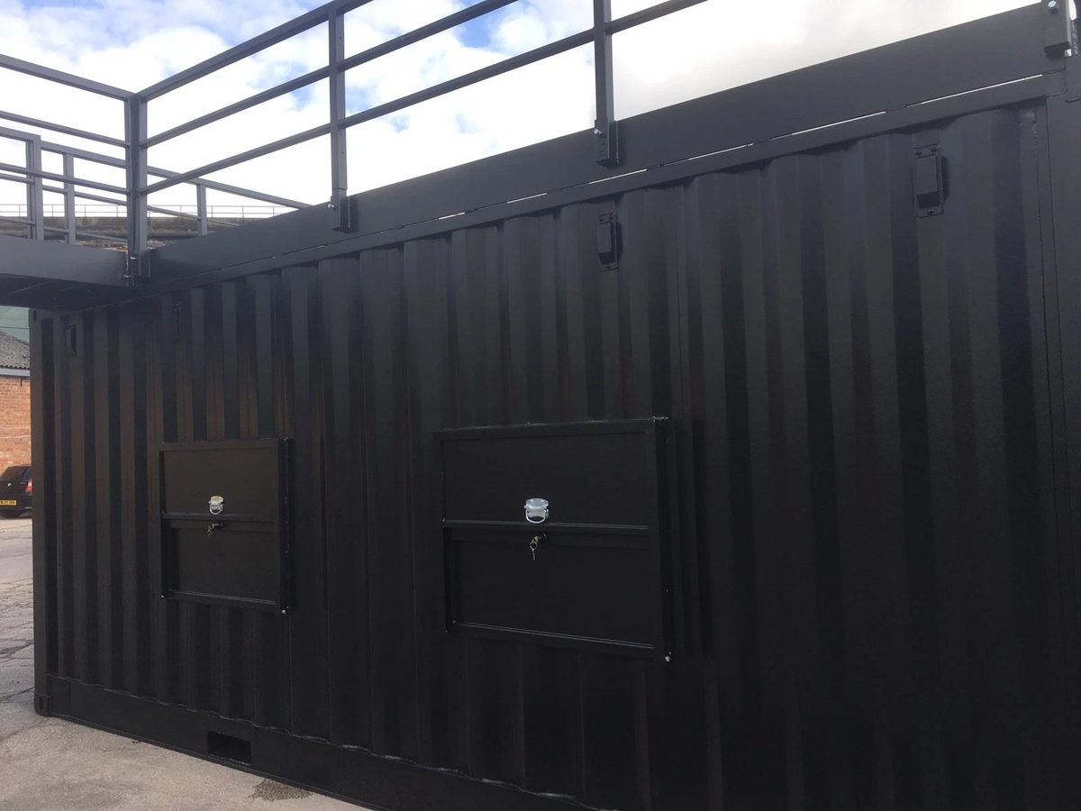 20ft Converted Shipping Container – Serving Hatches and Roof Deck – black container side with two closed hatches and rooftop railings