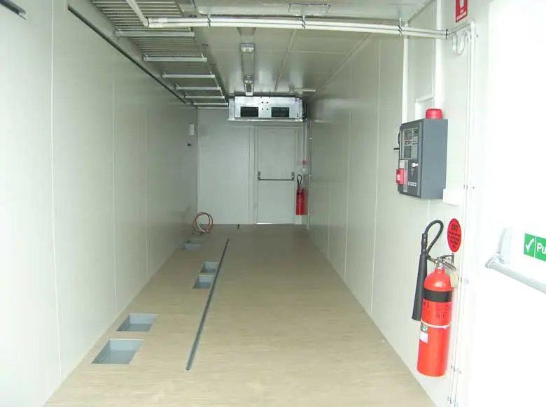 20 ft Switch Room Container – Insulated Panels – Long clean white interior corridor with fire extinguishers and ceiling mounted cable trays