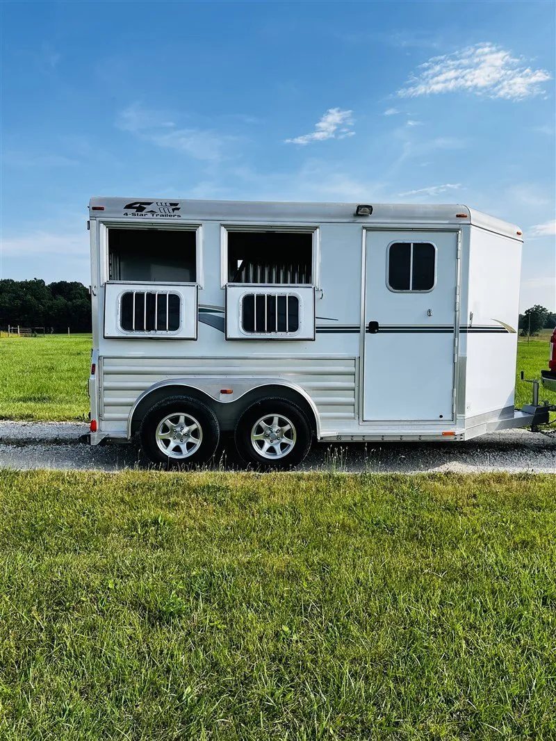 2015 4 Star 2 Horse Bumper Pull – Slant Load, Rear Tack – Exterior side view with windows open and bars visible on a gravel path