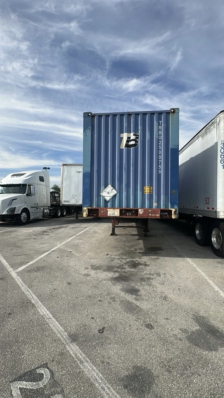 53ft High Cube Shipping Container – Used, Cargo Worthy – end view of blue container on chassis between trucks