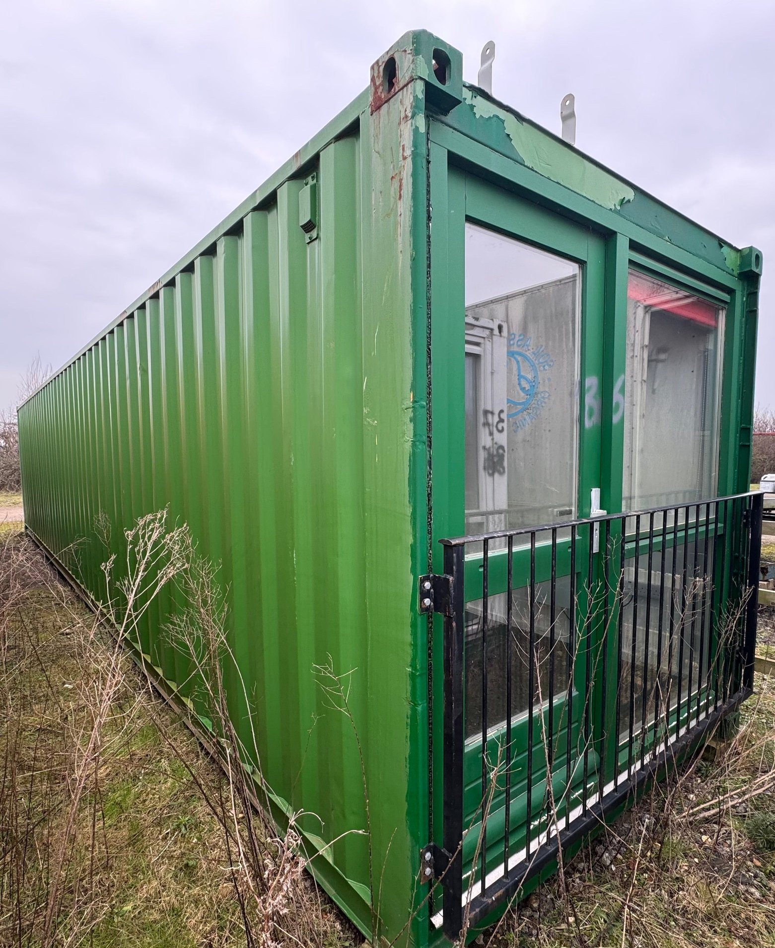 40ft Container Home – Two-Room Conversion – A 40ft unrefurbished green shipping container featuring a two-room conversion with installed glass entrance doors and safety railing
