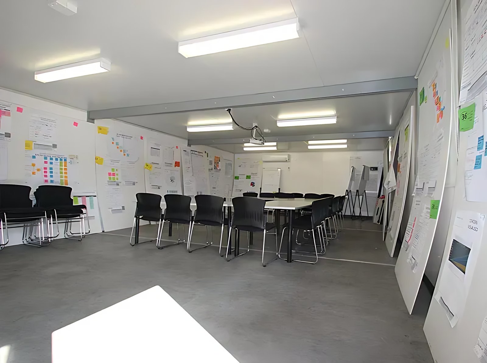 Custom Portable Steel Building – Office, Workshop or Storage – meeting room with tables, black chairs and wall charts