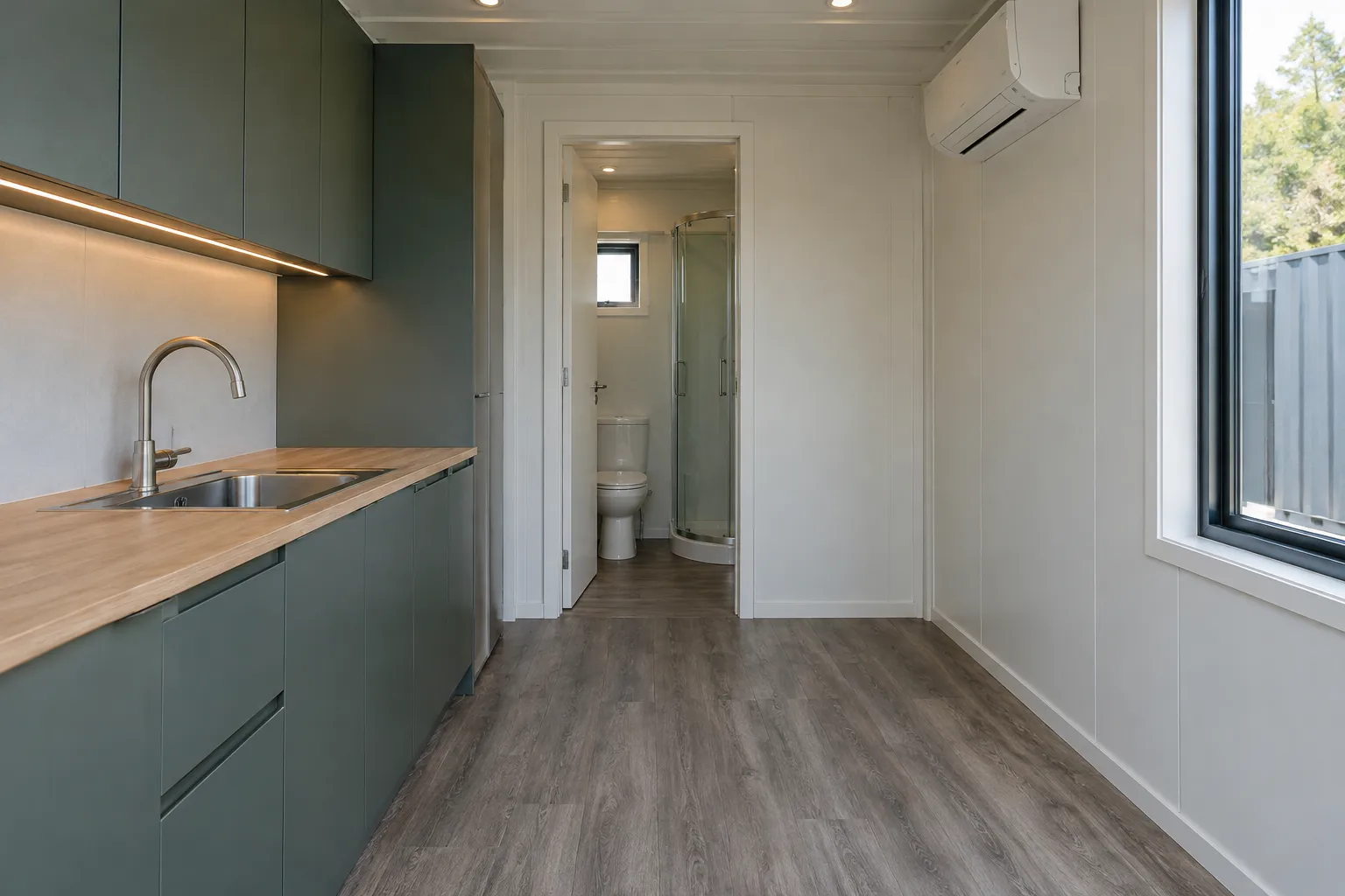 Finished container home interior showing built-in kitchen, bathroom doorway and HVAC equipment