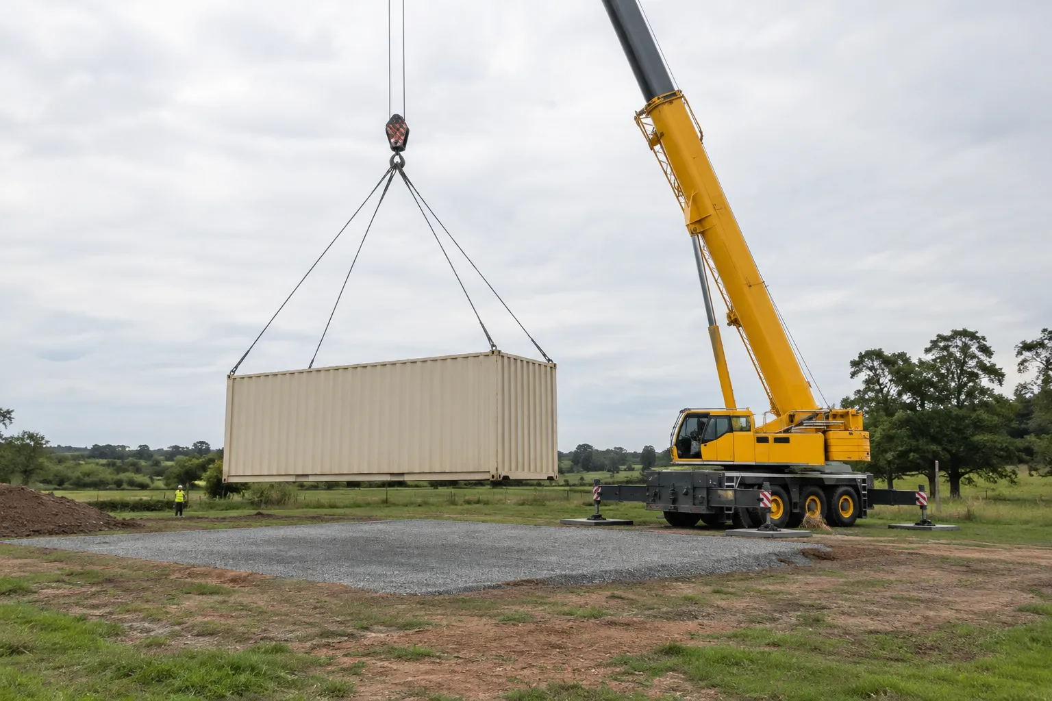 Crane offloading a container onto prepared ground for a delivered price comparison